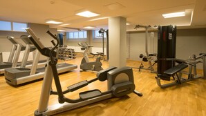 Un gimnasio con cintas de correr, elípticas y equipo de levantamiento de pesas.