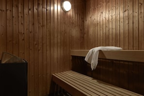 Una sauna de madera con un banco y una toalla colgada en la pared.