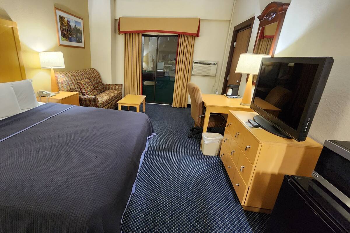 A hotel room with a large bed, a desk, a television, and a chair.