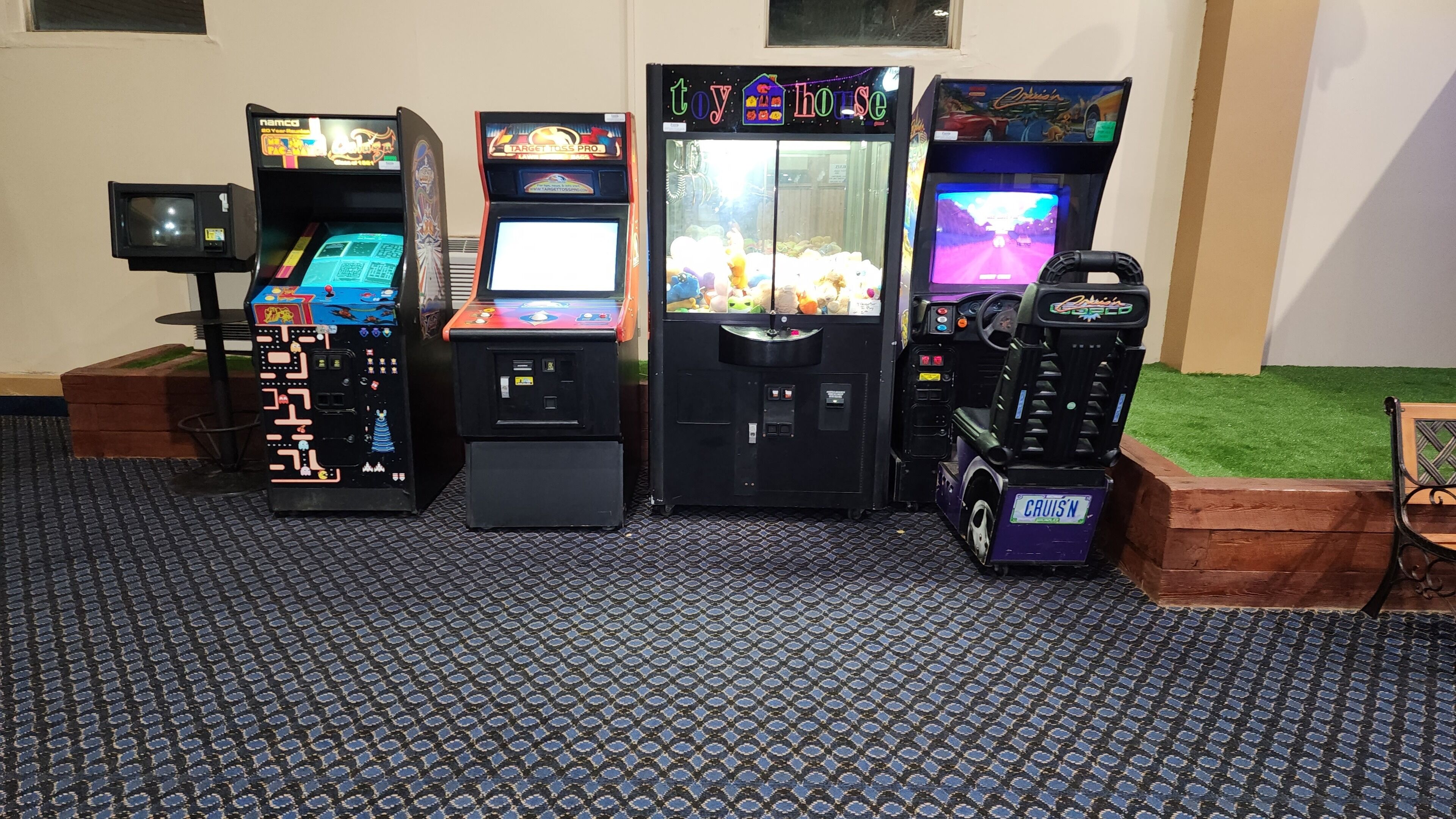 Four arcade machines lined up against a wall with a patterned floor.