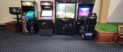 Quatre bornes d’arcade étaient alignées contre un mur, devant un sol à motifs.