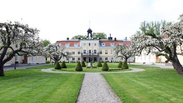 A large, multi-story building with a central entrance, surrounded by well-manicured lawns and trees.
