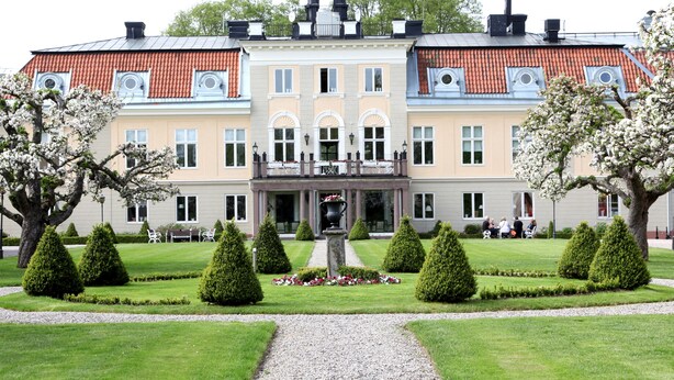 Un grand bâtiment à deux étages, doté d’une façade symétrique, d’une entrée centrale surmontée d’un arc décoratif et d’une petite tour au sommet.