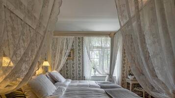 Un dormitorio con cama, mesita de noche, lámpara y cortinas traslúcidas.
