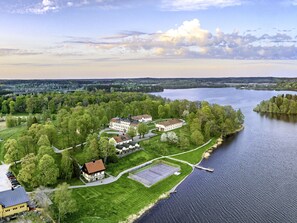 A riverside property with multiple buildings, a tennis court, and a dock. - Södertuna Slott (Gnesta)