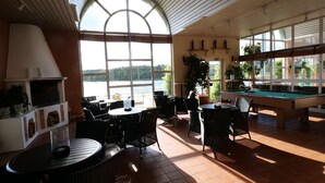 Un espace intérieur lumineux, avec une table de billard, un coin salon et une cheminée.