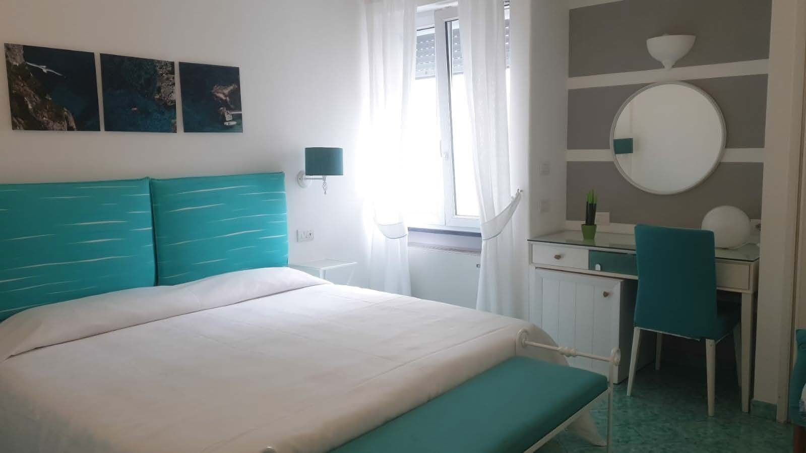 A bedroom with a bed, a desk, and a chair.