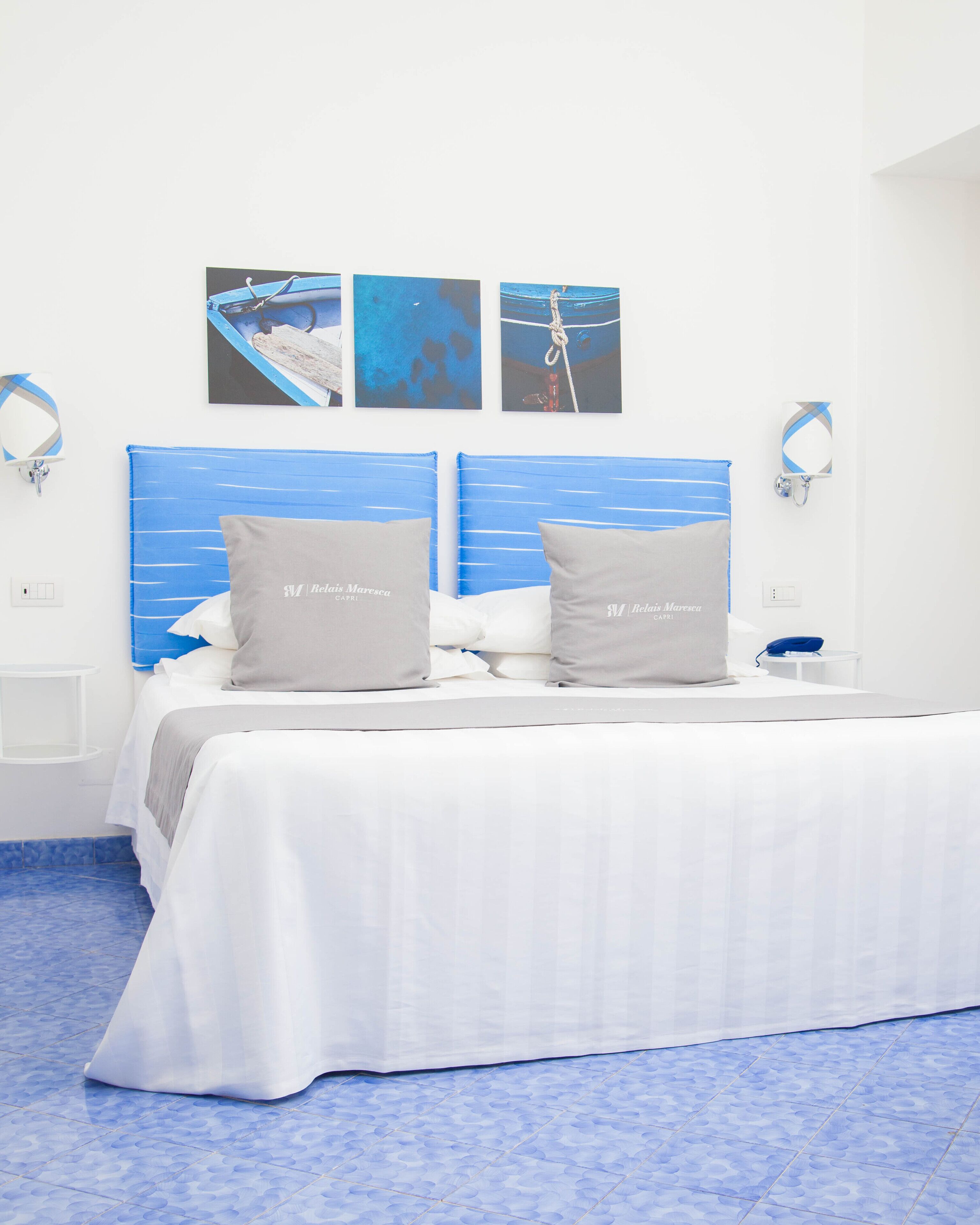 A hotel room with a bed, two pillows, a nightstand, a mirror, and artwork on the wall.