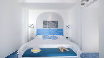 Een keurig opgemaakt hotelkamer met een bed, nachtkastjes, een hoed en schoenen op het bed.