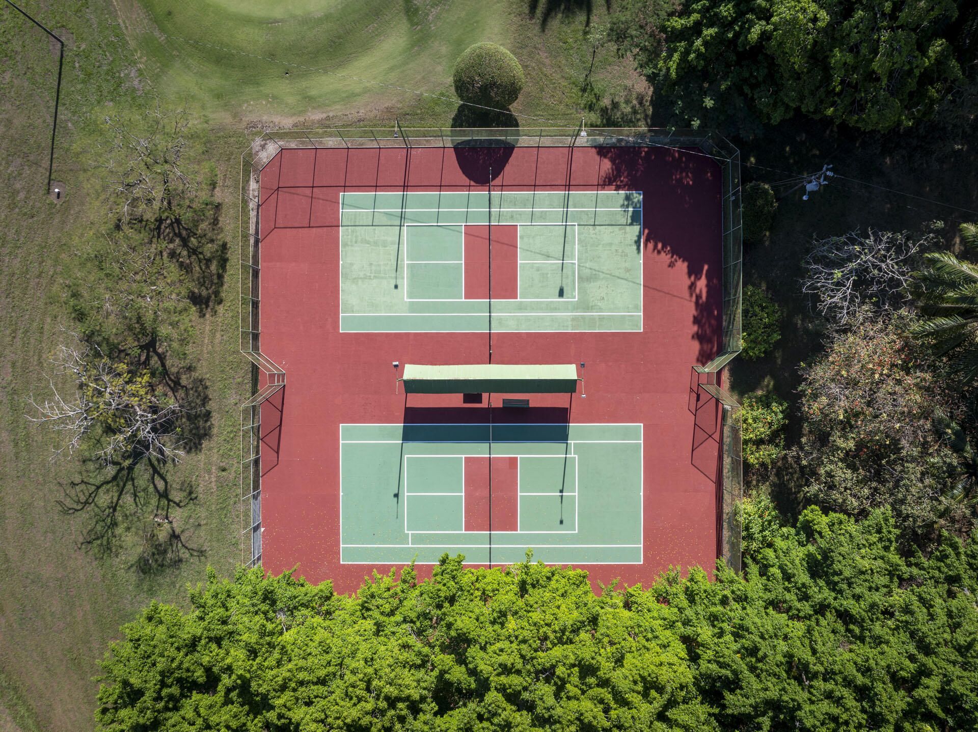 An aerial view of a tennis court surrounded by trees and grass.