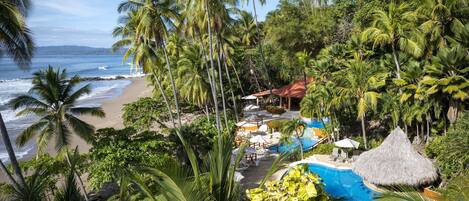 A tropical resort with a pool, beach, and palm trees.