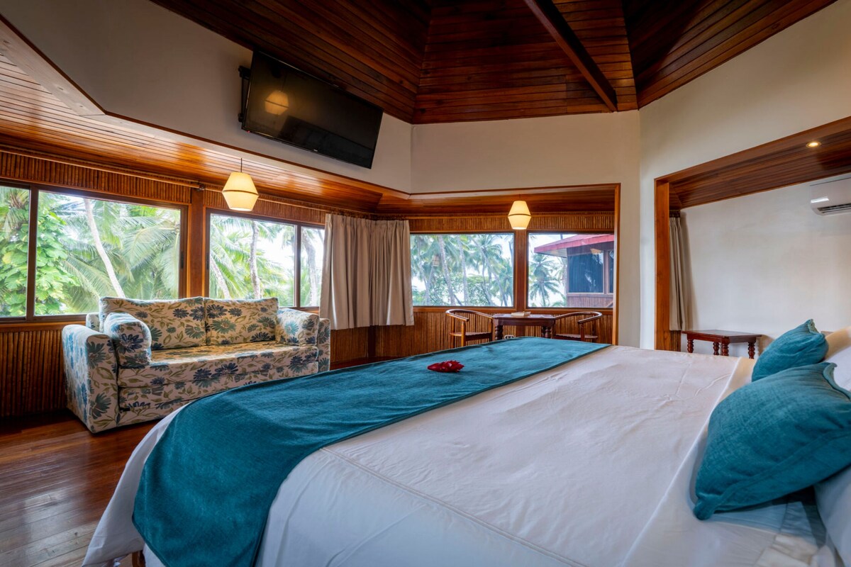 A bedroom with a bed, a sofa, a table, and a TV.