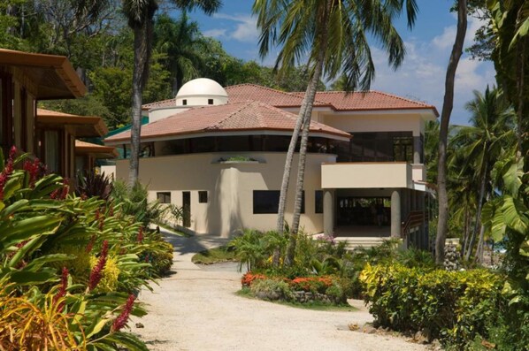 A modern two-story building with a dome on the roof, surrounded by lush tropical vegetation. - Tango Mar Beachfront Boutique Hotel & Villas (Cóbano)