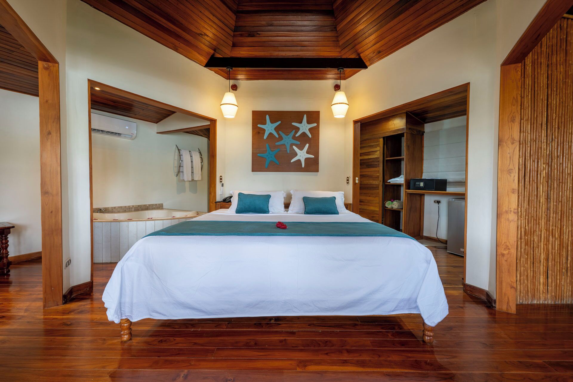 Une chambre spacieuse avec un grand lit, des poutres apparentes en bois au plafond et une décoration murale représentant une étoile de mer.