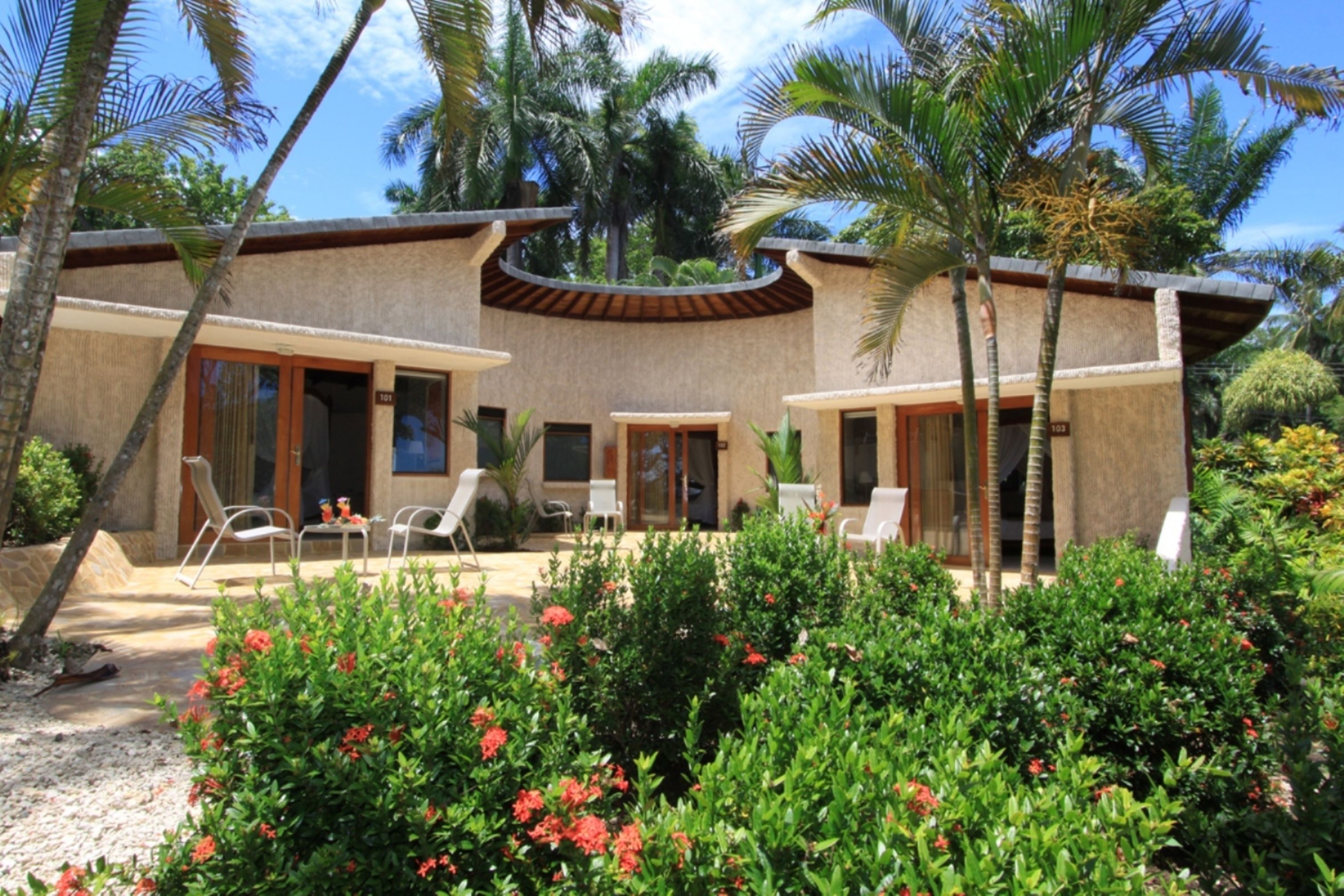 A resort with a pool area, outdoor seating, and lush tropical landscaping.