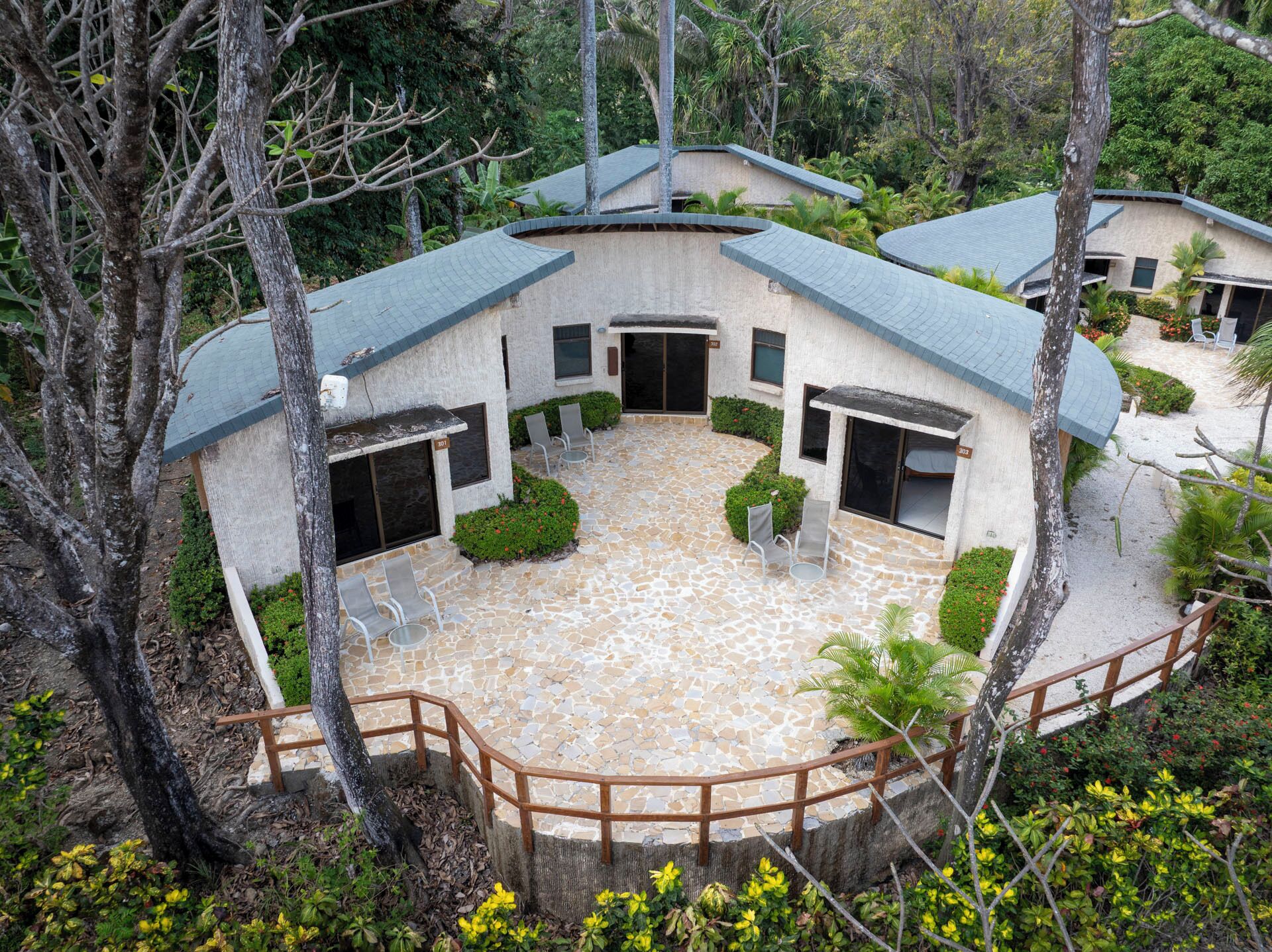 Un edificio circular con un patio de piedra, rodeado de árboles y vegetación.