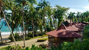A beachfront resort with multiple bungalow-style buildings, palm trees, and a sandy beach.