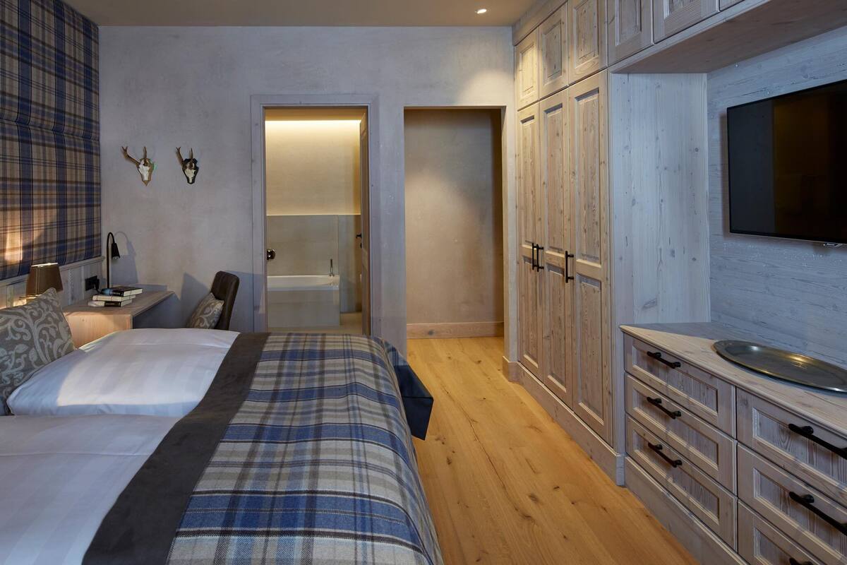 Ein Schlafzimmer mit einem großen Bett, einem an der Wand montierten Fernseher und Holzschränken.