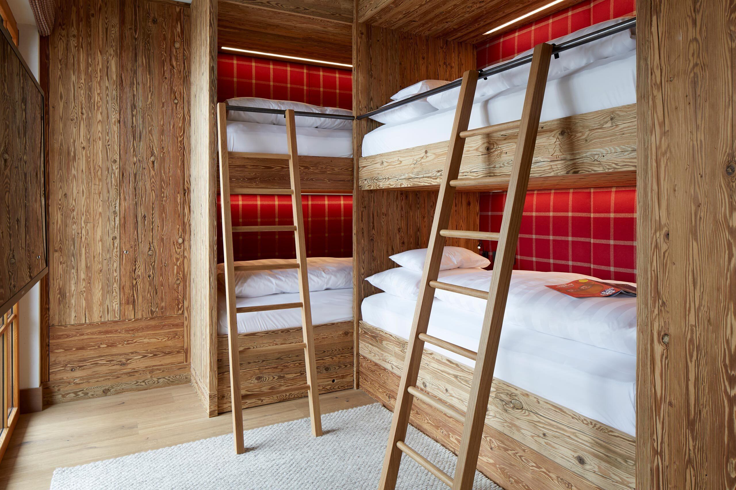 A wooden bunk bed room with a red checkered wall and a white carpet.