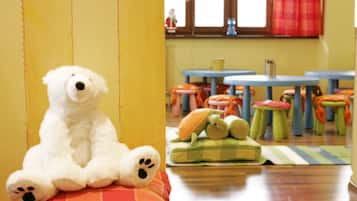Children can play and socialize in this inviting space with a plush teddy bear and comfortable seating.
