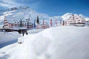 Een gebouw bedekt met sneeuw, met verschillende vlaggen, een kerktoren en een berg op de achtergrond.