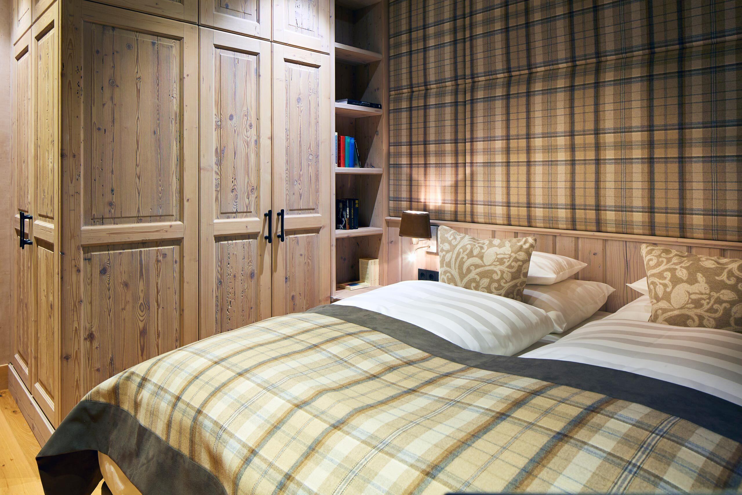 Ein Schlafzimmer mit Bett, Kleiderschrank und einem Regal mit Büchern.