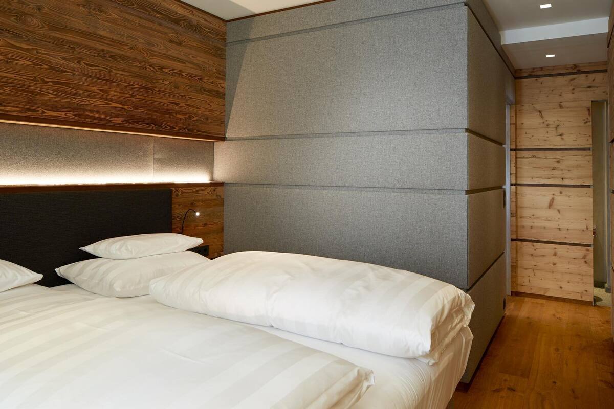 Ein modernes Schlafzimmer mit einem großen Bett, einem Holzkopfende und einer grauen Akzentwand.