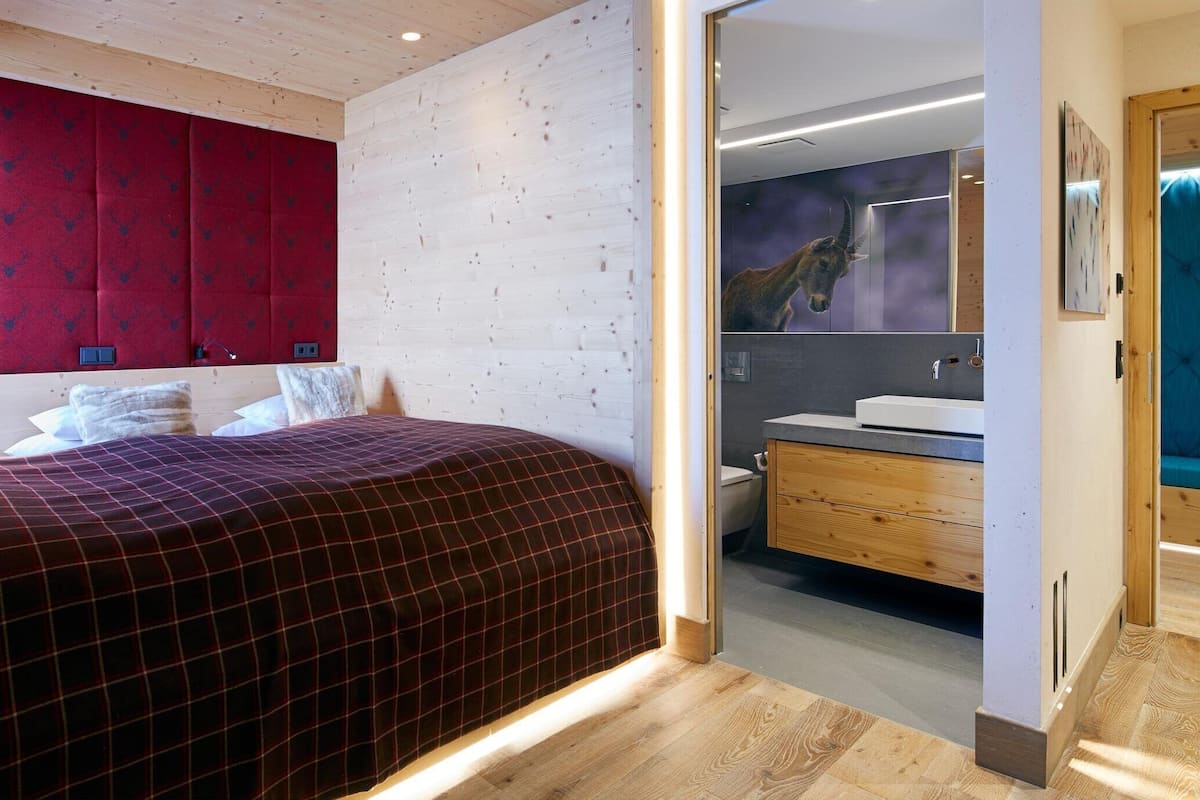 Ein modernes Schlafzimmer mit einem großen Bett, einer roten Kopfteil und einem Holzboden.