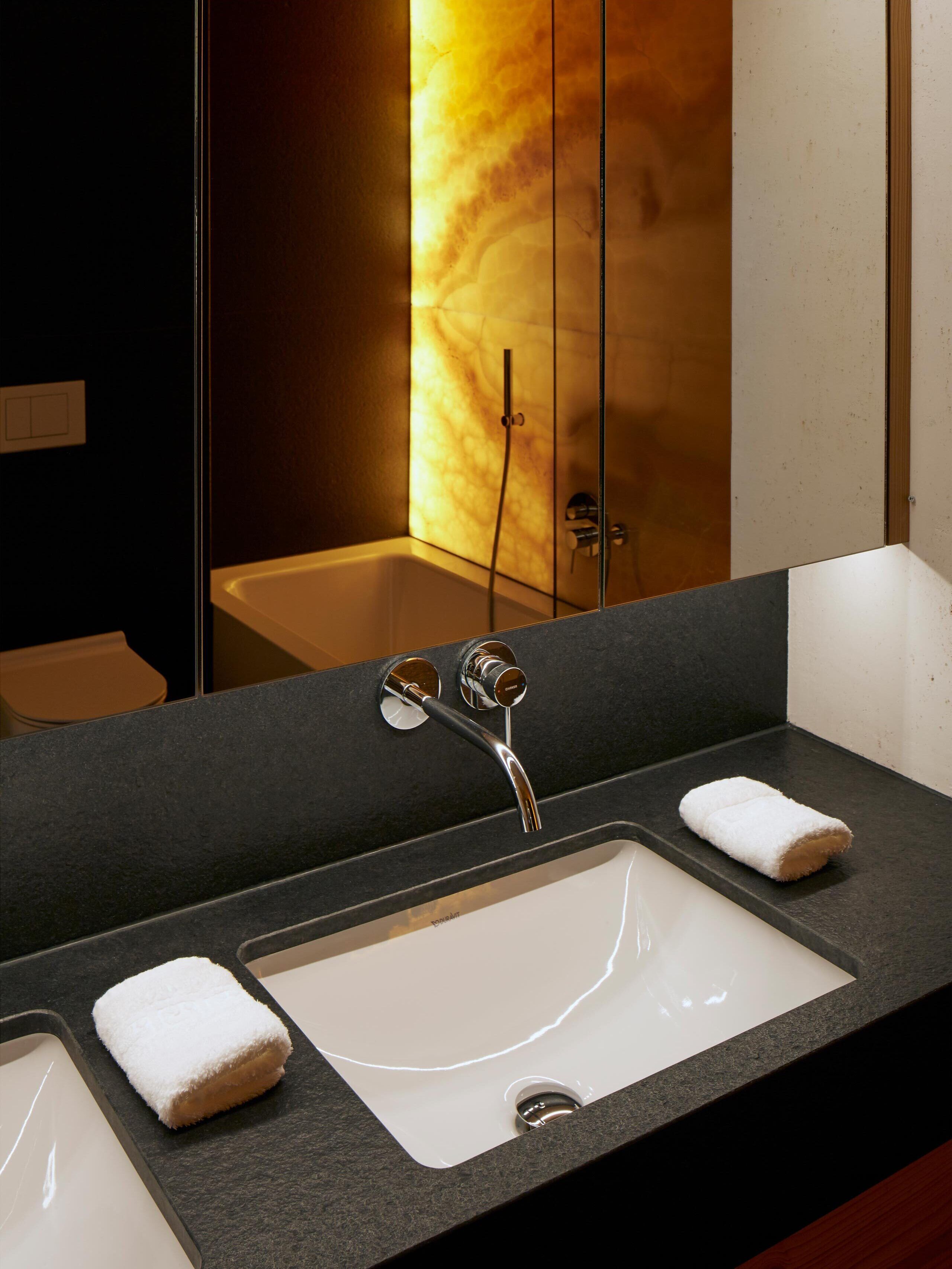 Une salle de bain moderne avec un grand miroir, deux lavabos et une douche.