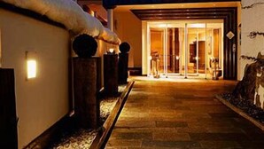 A hotel entrance with a wooden pathway leading to a glass door. - Hotel Paradies (Ftan)