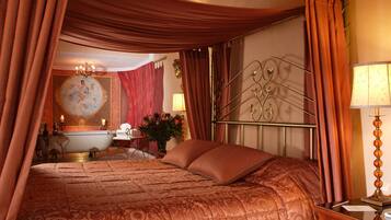 A bedroom with a large bed, a nightstand, a lamp, and a mirror.