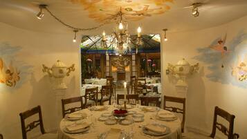 A dining area with a chandelier, ornate wall decorations, and a large mirror.