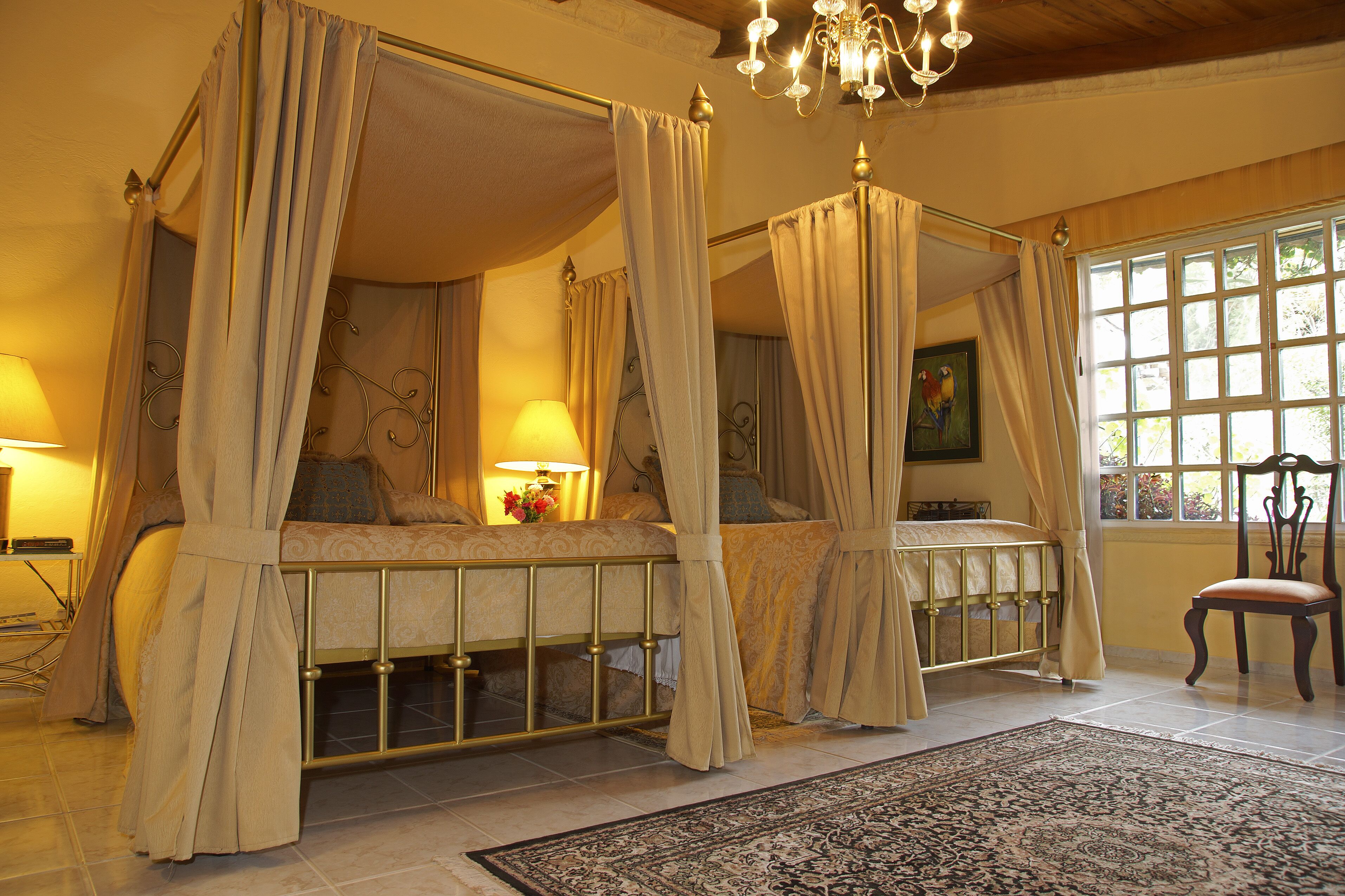 Una cama con dosel y cortinas, un candelabro y vistas del exterior a través de una ventana.