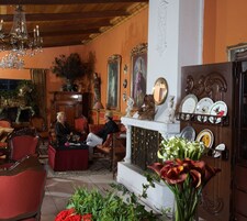 Amplia sala de estar con chimenea, sillones tapizados en rojo y una araña.