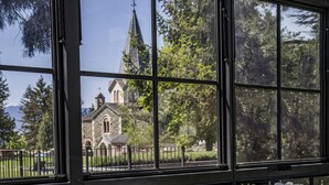A gym with exercise equipment, a water dispenser, and a view of a church through large windows. - Torre del Remei (Bolvir)