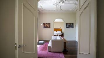 Un pasillo que conduce a un dormitorio con una cama, un banco y un escritorio.