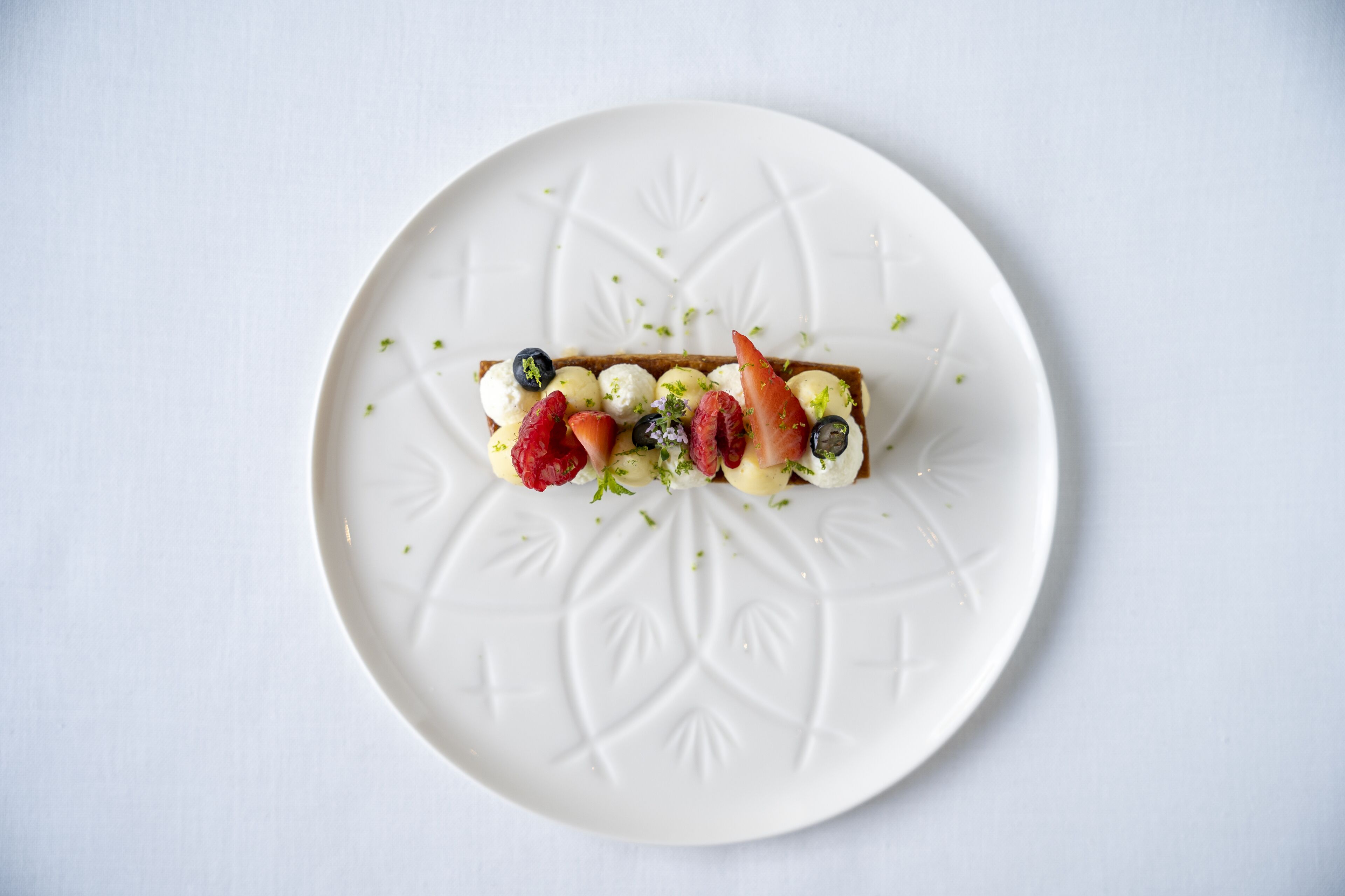 Un dessert servi dans une assiette blanche ornée d’un motif décoratif.