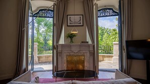 A room with a fireplace, a sofa, and a view of a garden through large windows. - Torre del Remei (Bolvir)
