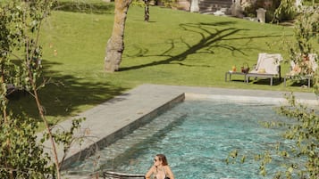 Een seizoensgebonden buitenzwembad en ligstoelen