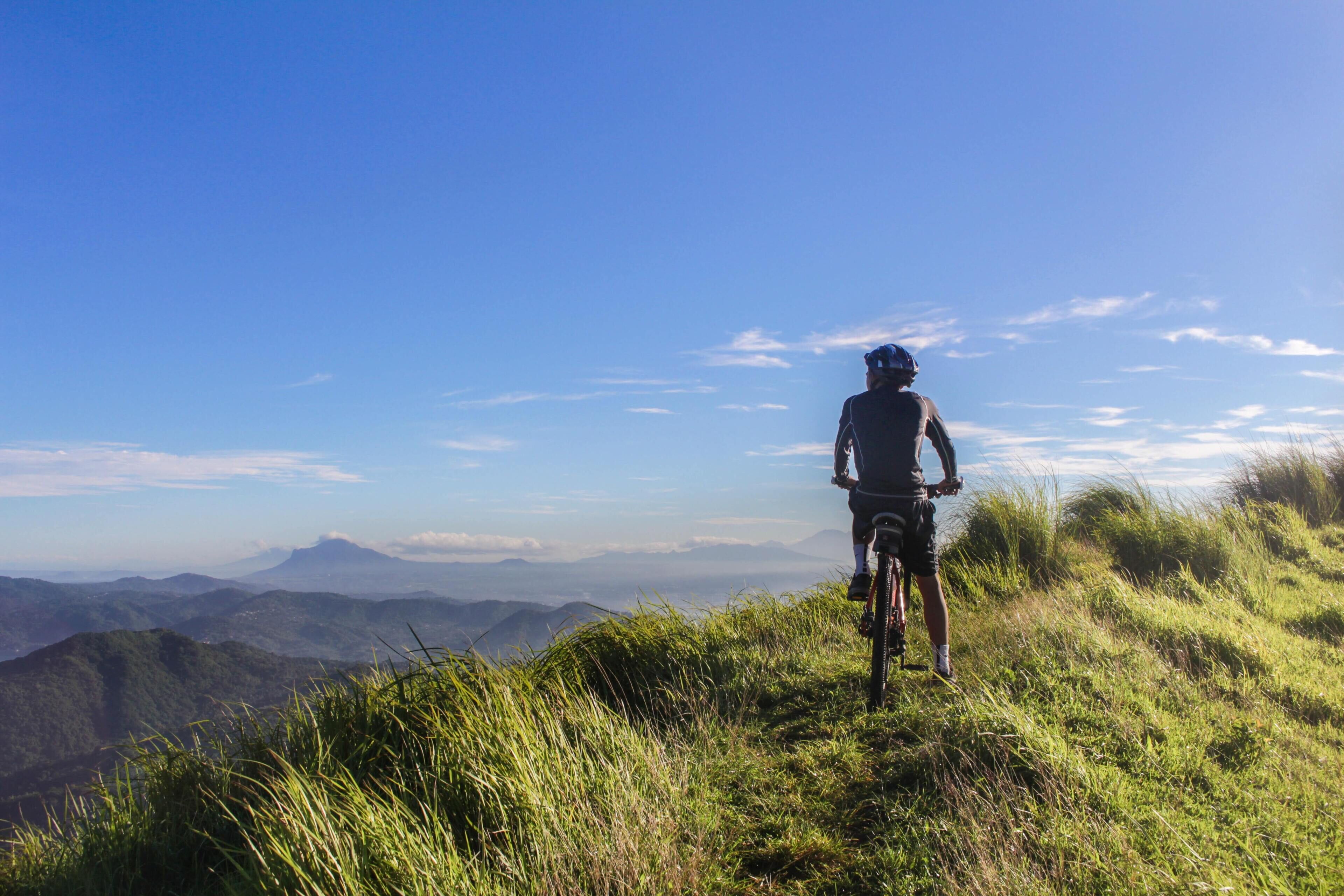 Una persona en bicicleta de montaña contemplando un paisaje montañoso.