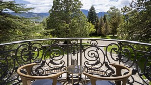 A balcony with wrought iron railings, two wicker chairs, and a small round table. - Torre del Remei (Bolvir)