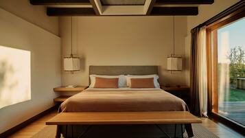 A modern bedroom with a large bed, bedside tables, a bench, and a view of the outdoors.