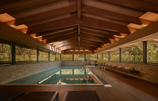 Una piscina interior con techo alto y amplios ventanales.