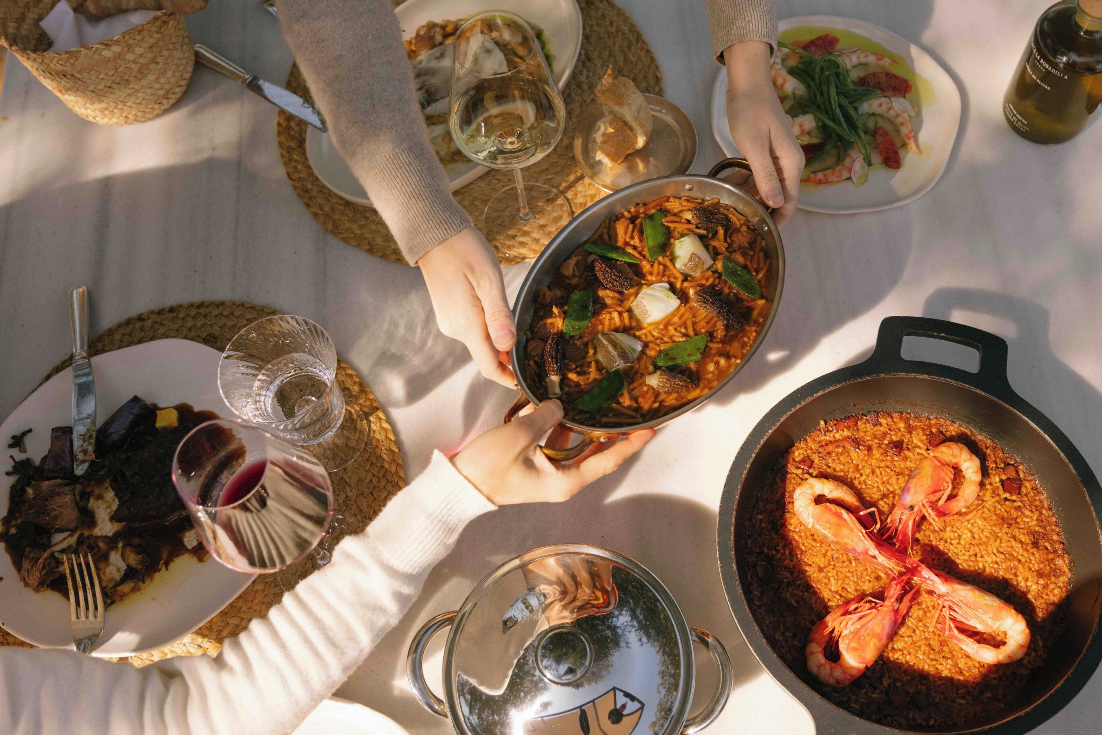 Une table à manger dressée avec différents plats, notamment des fruits de mer et un plat de riz.