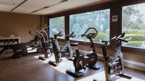Een fitnessruimte met hometrainers, een gewichtbank en een kleine tafel met een waterfles.