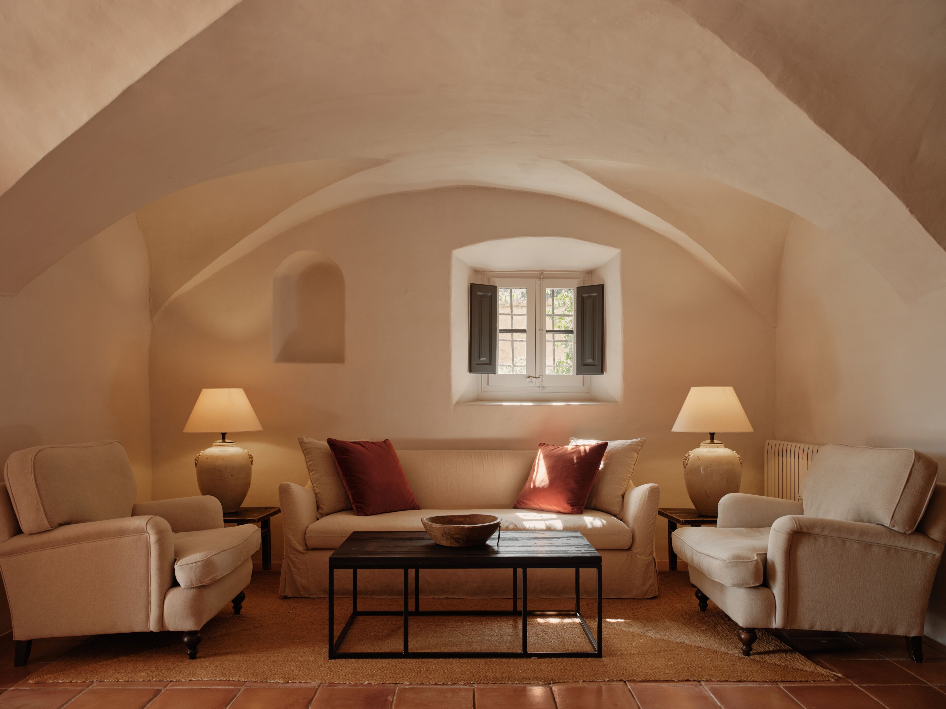 A cozy room with a vaulted ceiling, two armchairs, a sofa, a coffee table, and two lamps.