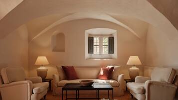 Una habitación acogedora con techo abovedado, dos sillones, un sofá, una mesita de centro y dos lámparas.