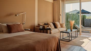 A hotel room with a large bed, a sofa, a small table, and a view of the outdoors.