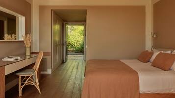 Un dormitorio con cama, escritorio y silla. Se ve una puerta que da a un jardín.