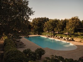 Una piscina cubierta, una piscina al aire libre, sombrillas